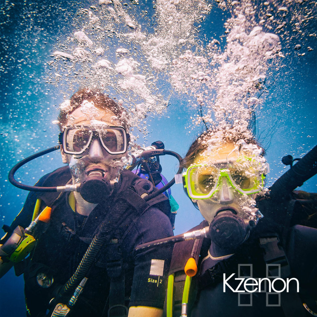 Man and woman scuba divers in tropical sea diving up
