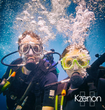 Man and woman scuba divers in tropical sea diving up