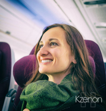 Happy woman tourist with green scarf during flight in plane to her vacation