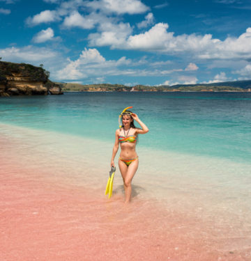 Girl in snorkeling gear standing on pink beach